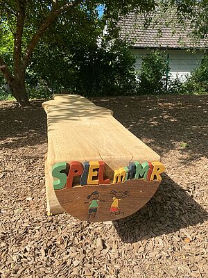 Soziale Bank mit Schnitzereien "Spiel mit mir" und "Blume" an den Seiten