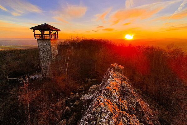 Sonnenuntergang mit Teufelsfels und Aussichtsturm bei Hennweiler im Vordergrund