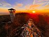 Sonnenuntergang mit Teufelsfels und Aussichtsturm bei Hennweiler im Vordergrund