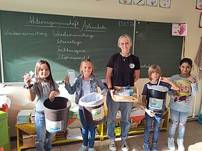 Schüler vor Tafel beim Vorzeigen verschiedener Müllarten