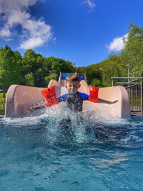 Kind mit Schwimmflügeln auf einer Rutsche im Jahnbad Kirn