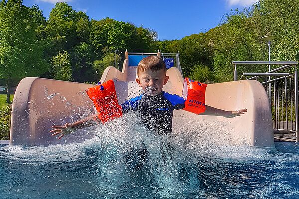 Kind mit Schwimmflügeln auf einer Rutsche im Jahnbad Kirn